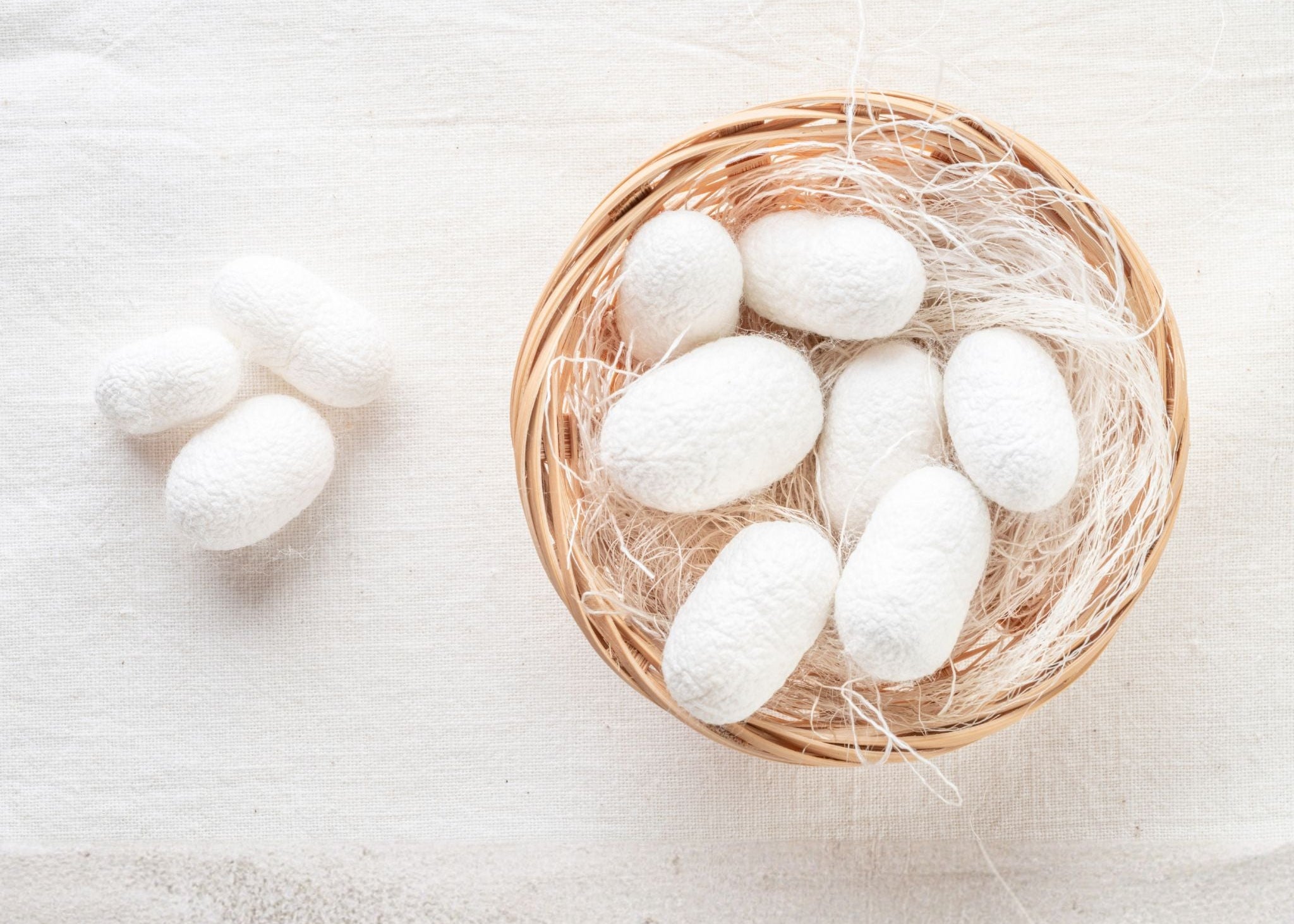 Silkworm cocoons in a small woven basket on a light background
