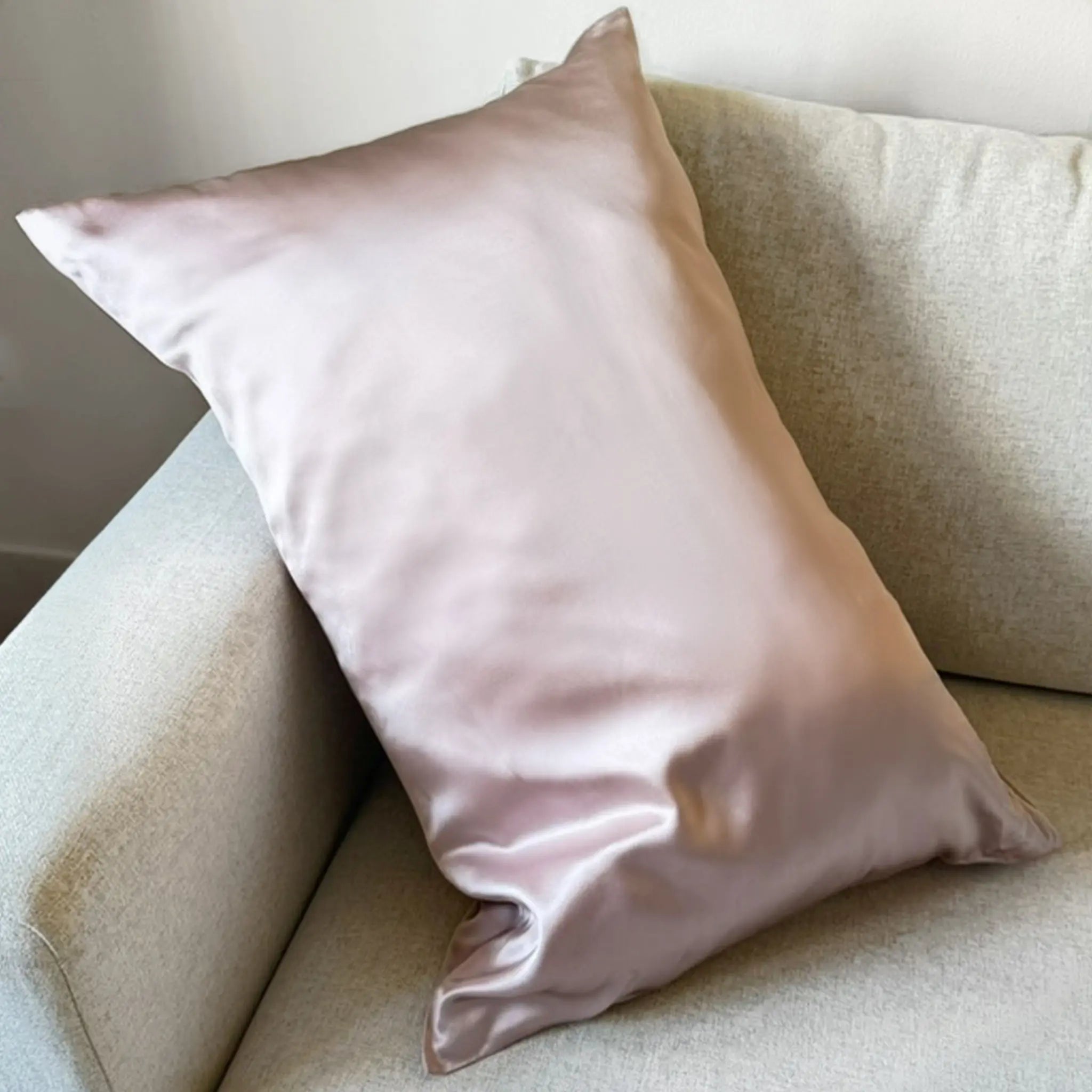 Pillow in Taupe silk pillowcase on a beige sofa against a neutral wall — Silk Souq pure mulberry silk home decor.