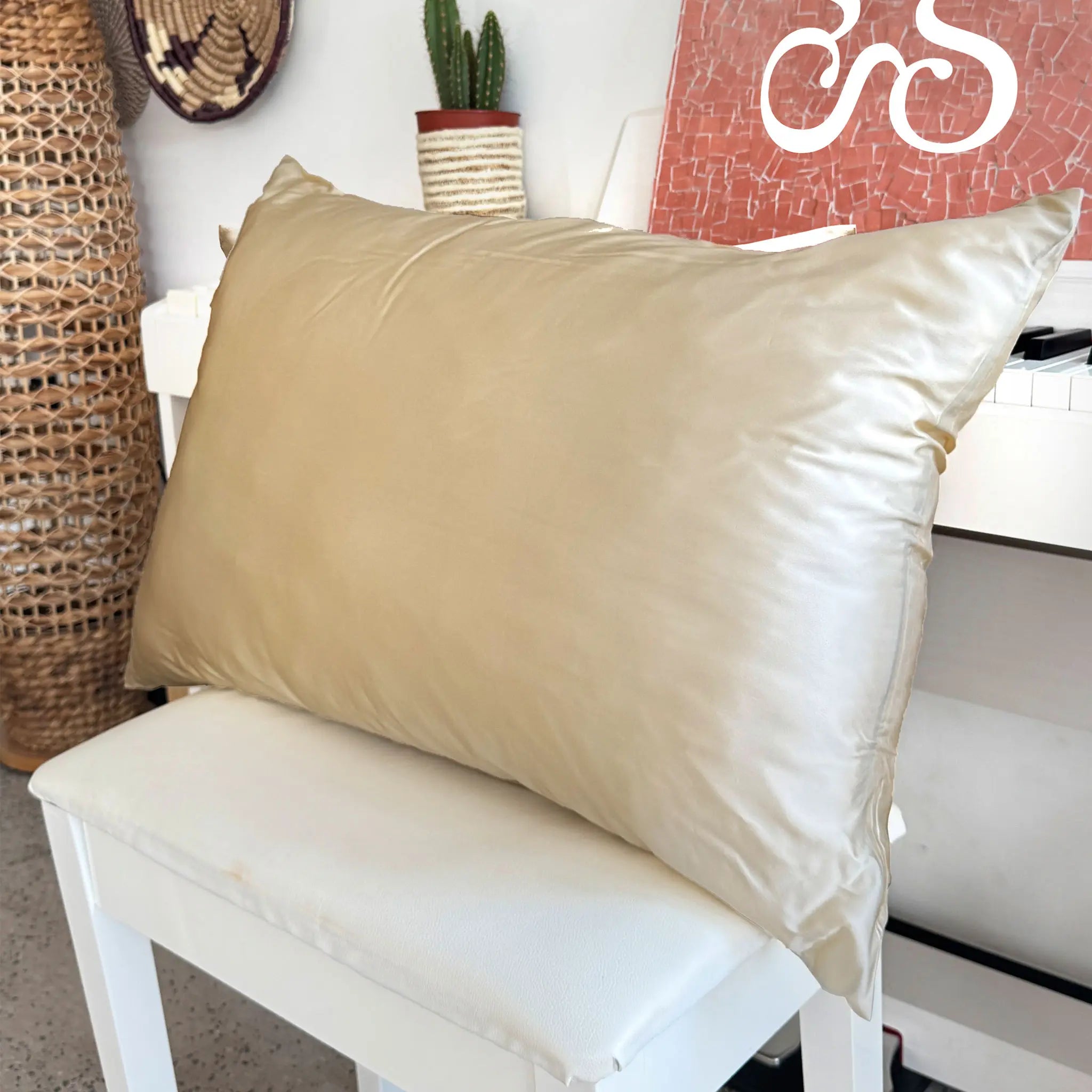 Pillow with Pure mulberry silk pillowcase in Mocha Taupe color on a white chair with decorative items in the background — Silk Souq 22 momme luxury silk pillowcase