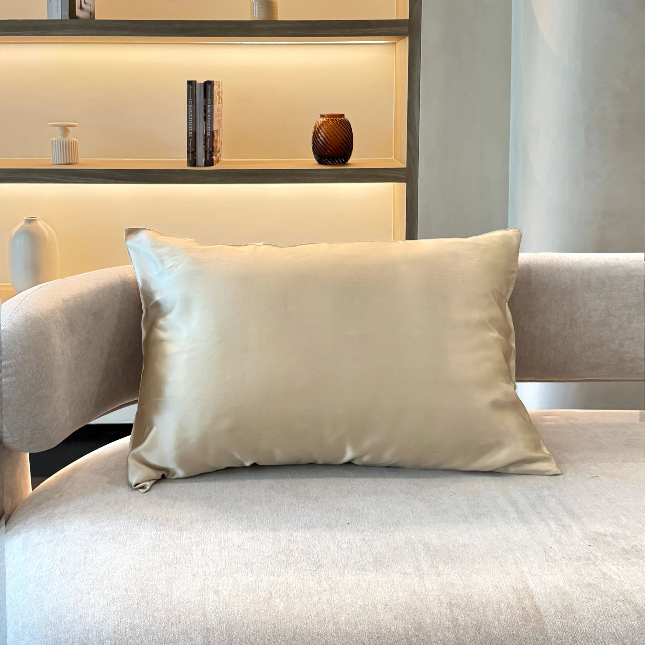 Pillow with Pure mulberry silk pillowcase in Mocha Taupe color on a sofa with decorative vases on a shelf in the background — Silk Souq 22 momme luxury silk pillowcase